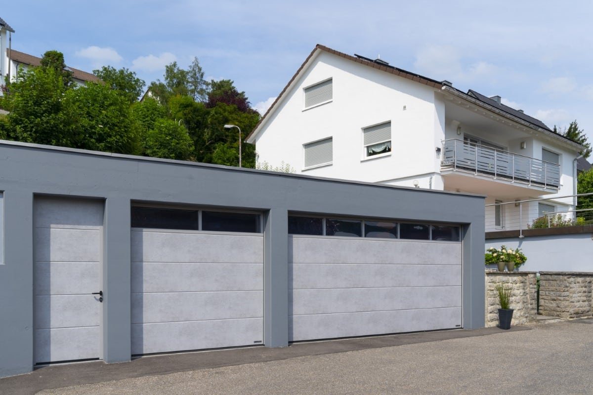 Zwei Garagentore nebeneinander vor einem weißen Wohnhaus