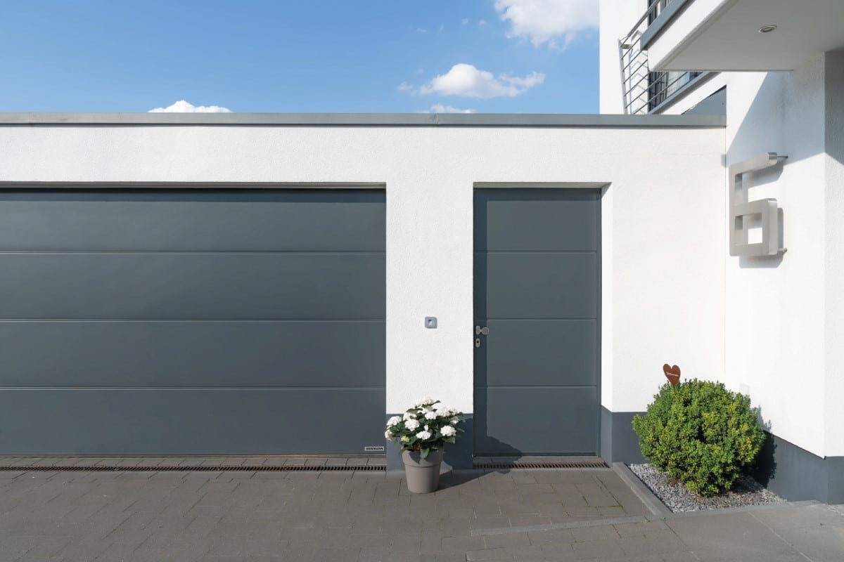 Garage mit Garagentor und Nebentür an einem weißen Gebäude