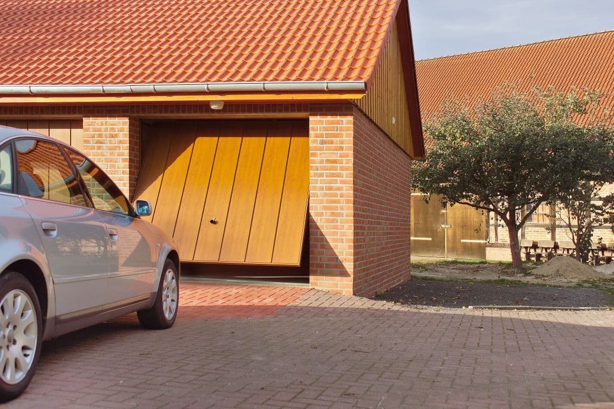 Gemauerte Garage mit teilweise geöffnetem Garagentor, davor ein geparktes Auto